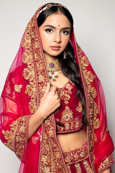 Bridal makeup: a model in a red lehenga with gold embroidery, dupatta draped over the head