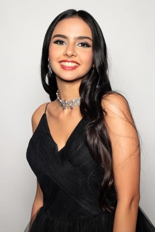 Soft glam makeup: a model smiling in a black gown with silver jewellery