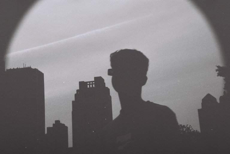 Black and white: the silhouette of a person against a city skyline, seen through a circular vignette