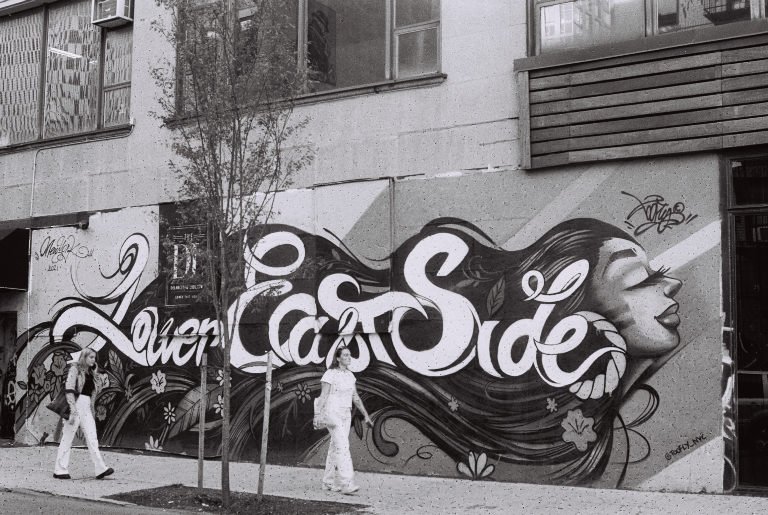 Black and white: a Lower East Side mural on a building wall as two people walk past