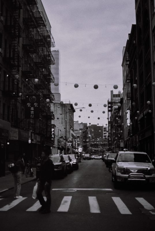 A Chinatown street strung with lanterns, a pedestrian crossing in the foreground