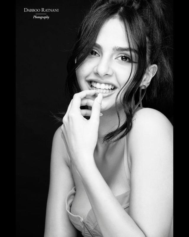 Black and white portrait of Sargam laughing with a finger against her lips