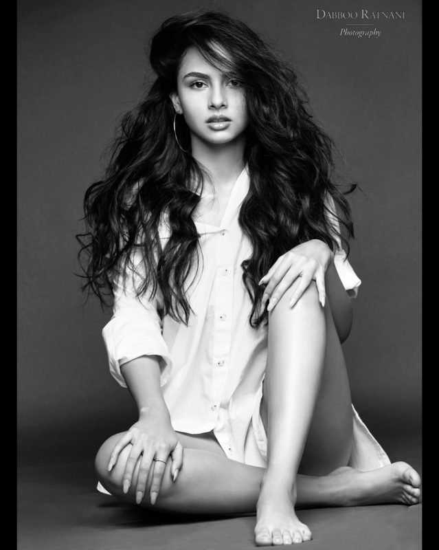 Black and white full-length portrait of Sargam seated on the floor in an oversized white shirt