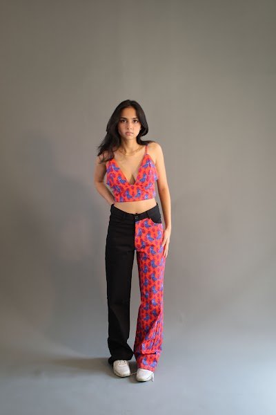 Rea by Rhea lookbook: a model standing in a red printed crop top and matching trousers with trainers