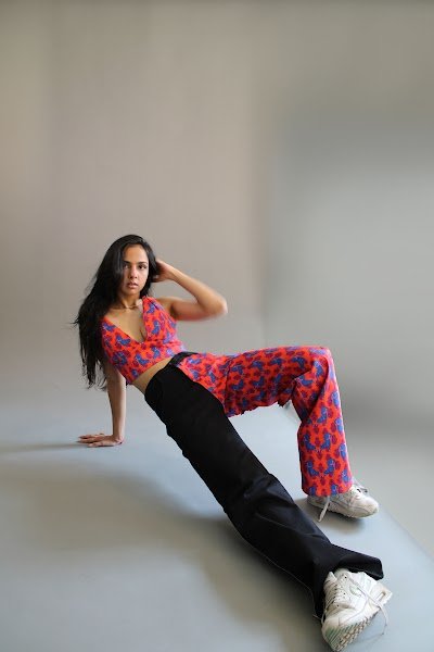 Rea by Rhea lookbook: a model leaning back on one arm on the studio floor in a red printed co-ord