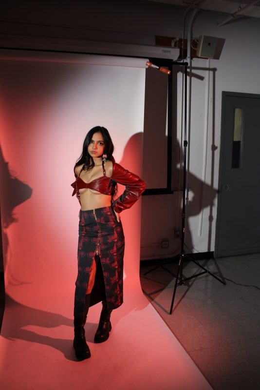 Rea by Rhea lookbook: full-length shot of a floral skirt with a high slit, studio lights in frame, red wash