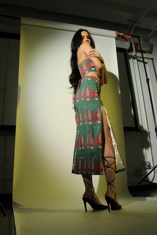 Rea by Rhea lookbook: a model on pointed heels in a green printed co-ord, studio lights in frame