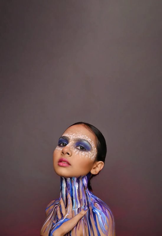 Editorial makeup: blue and purple paint running down the neck, the model looking upward